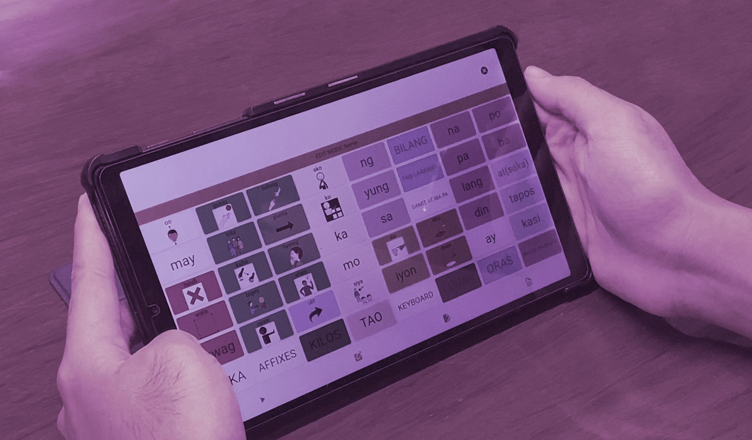 Child using AAC communication board with teacher